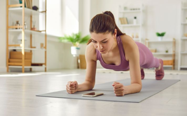 woman doing plank while watching her phone timer