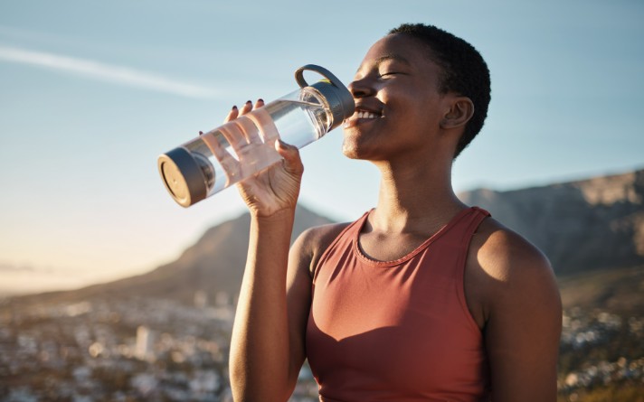 woman in a red tank top drinking water